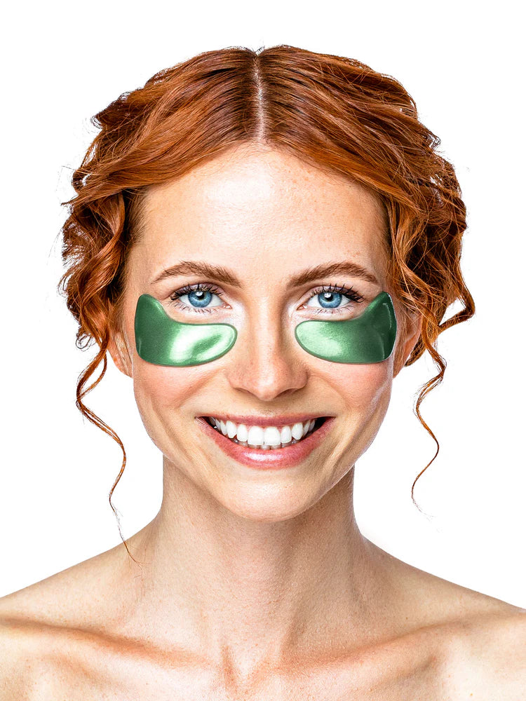 Woman wearing green eye patches on a white background